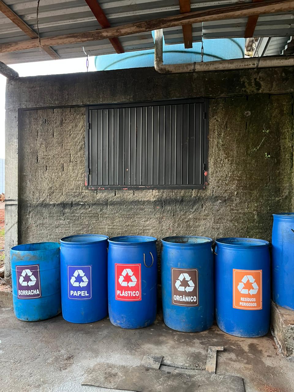 Tambores identificados para segregação de resíduos em área de armazenamento temporário