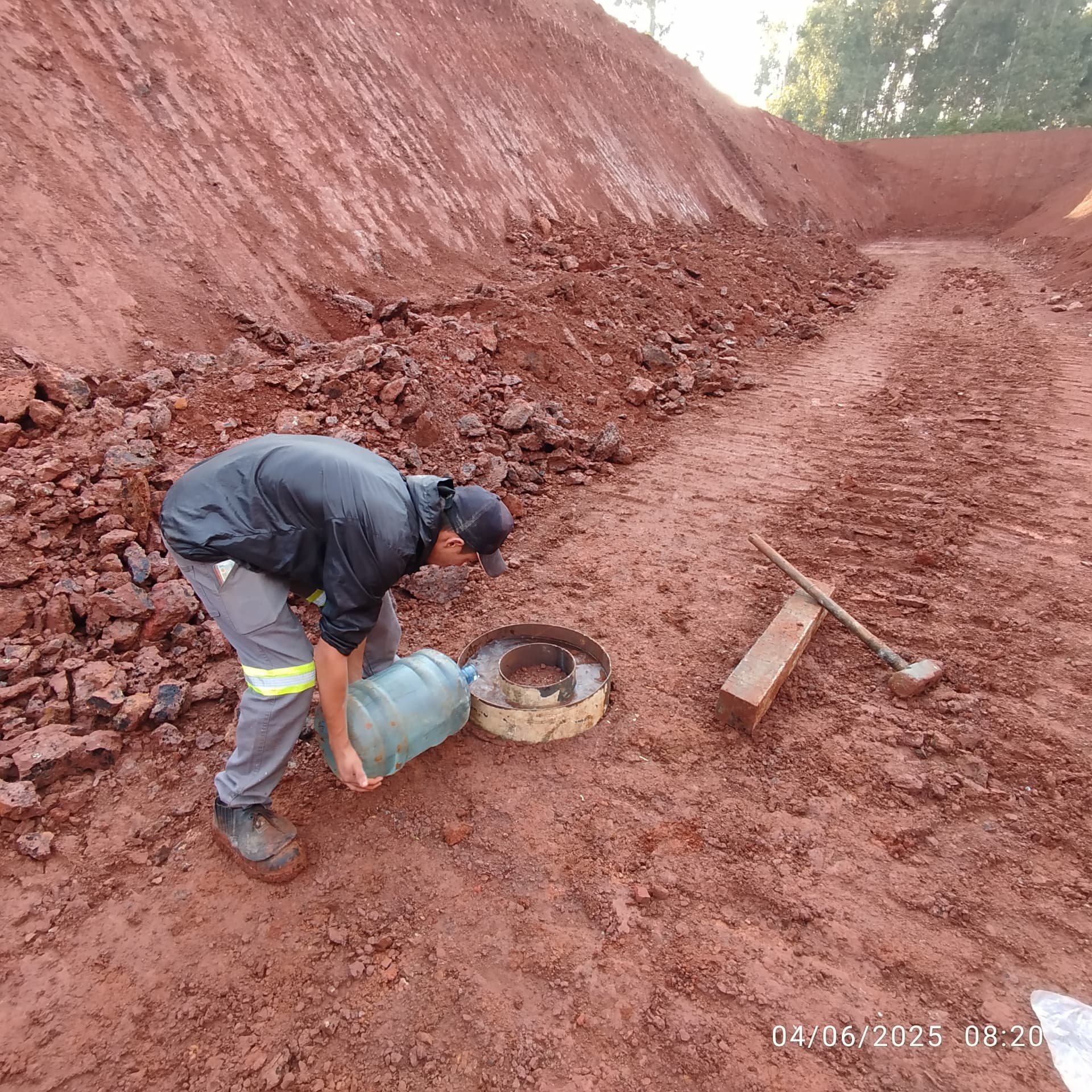 Aplicação de água em anel de ensaio de permeabilidade em área terraplanada